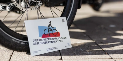 Die Wertgarantie Group ist der fahrradfreundlichste Arbeitgeber 2023. Schild mit Aufschrift "Fahrradfreundlichster Arbeitgeber" steht vor Fahrrad