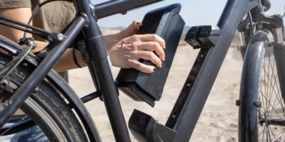 E-Bike Akku wird von einer Hand aus Fahrrad gelöst