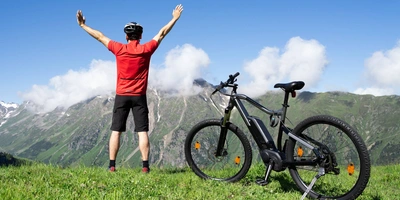 Diese Leistungen bietet dir in Amprio RMAG Motor Person steht neben einem E-Bike auf einer grünen Wiese