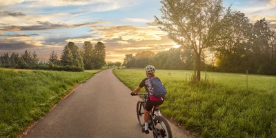 Frau fährt mit einem E-Bike auf einem Radweg durch die Natur in Baden-Württemberg