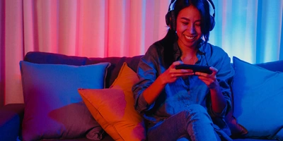 Es gibt viele großartige Bike Games zu entdecken Frau sitzt auf einem Sofa und spielt auf Smartphone