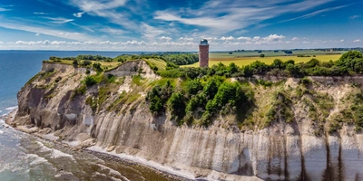Steilküste mit einem Leuchtturm und grünem Gras unter blauem Himmel der Insel Rügen