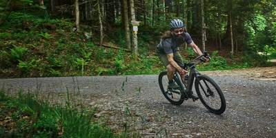 Mann fährt auf Canyon E-Gravel durch Wald.