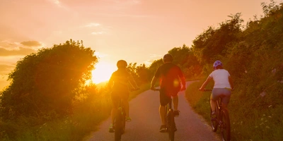 Centurion Text: Centurion No Pogo und weitere E-Bikes im Test Drei Radfahrer genießen den Sonnenuntergang auf einem ruhigen Weg.