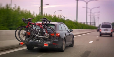 Auto fährt auf der Straße. Am Heck des Autos ist ein Fahrradträger befestigt.