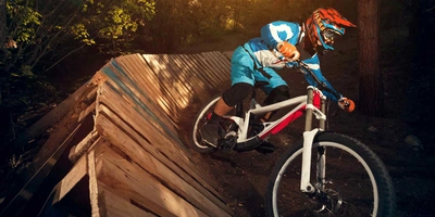 Darauf solltest du im Bikepark achten. Mounatinbiker fährt Downhill Strecke hinunter.