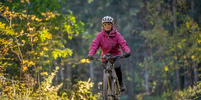Eine Frau fährt im Wald ihr E-Bike