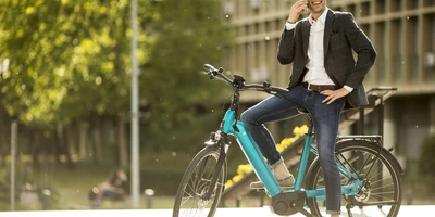 Mann sitzt auf einem stehenden Fahrrad und telefoniert