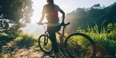 Person steht mit ihrem Mountainbike im Wald