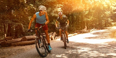 So sieht die Zukunft für E-Bikes aus. Zwei Männer fahren sportlich mit dem Mountainbike.