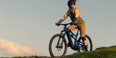 Frau mit Helm auf Mountainbike fährt Berg hinunter.