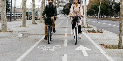 Zwei Personen fahren nebeneinander auf Fahrrädern über einen Radweg.