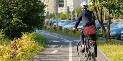 Diese Tipps solltest du für eine sichere Fahrt beachten. Mann auf Rad mit Helm fährt Fahrradweg entlang.