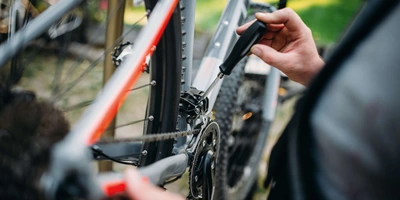 Mann schraubt an der Schaltung von einem Fahrrad.