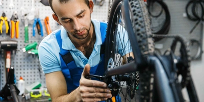 Mann führt Reparaturen an Fahrrad-Schaltung durch.