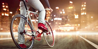 Eingangräder werden häufig in Stadtgebieten genutzt. Fixiefahrer fährt bei Nacht auf eine Stadt zu.