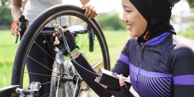 Frau pumpt das Fahrrad mit einer elektrischen Fahrradpumpe auf