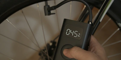 Elektrische-Fahrradpumpe-Test Hand, die ein digitales Luftdruckmessgerät an einem Fahrradreifen hält.