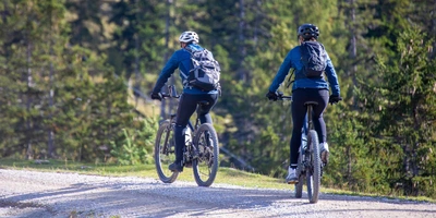 Zwei Frauen fahren auf E-Mountainbike durch die Berge.