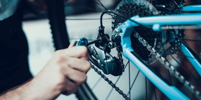 Person berührt die Fahrradschaltung eines blauen Fahrrads