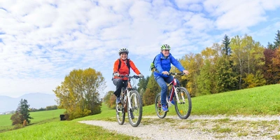 Fahrrad-Ergonomie: Mit einem perfekt auf den individuellen Körperbau eingestellten Fahrrad schmerzfrei unterwegs sein. Zwei Personen fahren in der Natur Fahrrad.