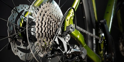 Detailansicht eines Fahrradschaltwerks mit grünem Rahmen und Bremsen.