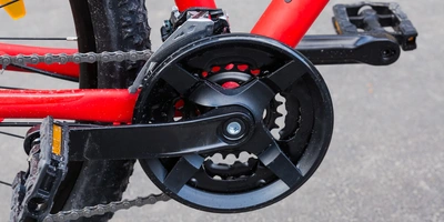 Fahrrad Tretlager wechseln: Ausbau & Tausch des Innenlagers Details des schwarzen Kettenblatts an einem roten Fahrradrahmen.