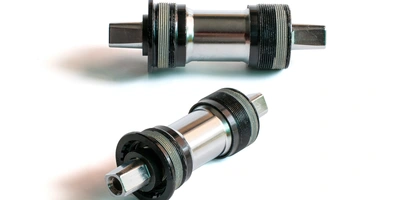 Zwei Fahrrad-Tretlager in metallischem Finish auf weißem Hintergrund.