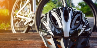 Ein Fahrradhelm liegt auf dem Tisch. Im Hintergrund befindet sich ein Mountainbike