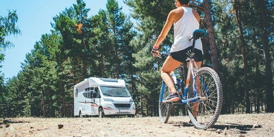 Frau auf einem Fahrrad blickt auf ein Wohnmobil