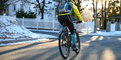 E-Bike fahren im Winter: Darauf musst du achten! Fahrradfahrer fährt im Winter auf Straße