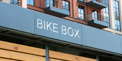Fahrradbox-Test: Das sind untere Sieger Schild mit der Aufschrift "BIKE BOX" an einer modernen Gebäude-Fassade.