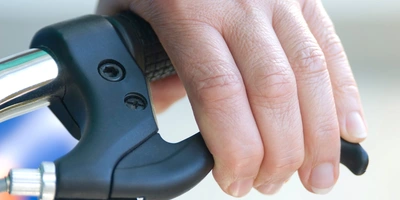 Um das Zweirad verkehrssicher zu halten, ist eine gut funktionierende Bremse das A und O Hand greift eine Fahrradbremse