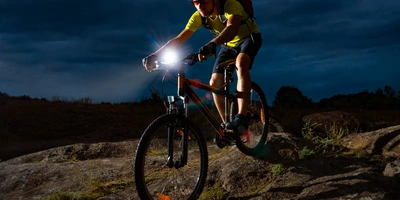 Mann fährt mit dem Fahrrad mit Licht im Dunkeln über einen Berg