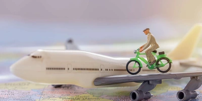 Fahrradmitnahme im Flugzeug Ein Spielzeug-Fahrrad fährt auf dem Tragflügel eines Spielzeug-Flugzeugs.