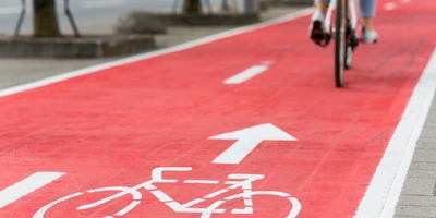 Radweg auf rotem Belag mit weißem Fahrradsymbol und Richtungspfeil