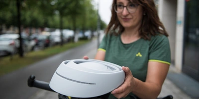 Radfahrerin hält zusammengefalteten Helm von Closca in der Hand.