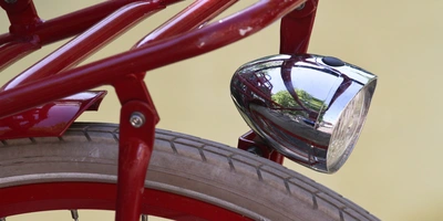 Roten Fahrradlicht mit glänzendem Gehäuse und Reifen im Hintergrund.