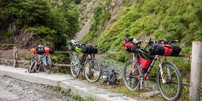 Drei Fahrräder in bergigem Gelände, die mit rot-schwarzen Bikepacking-Taschen versehen sind