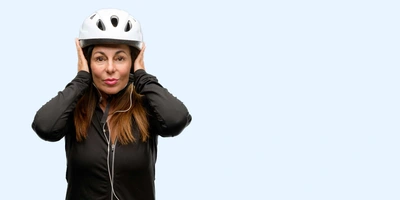 Frau mit aufgesetztem Fahrradhelm hält sich die Ohren zu