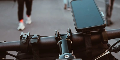 Handyhalterung Fahrrad Test: Welche Modelle überzeugen Blick auf den Lenker eines Fahrrads mit einem Smartphonehalter und Fußgängern im Hintergrund.