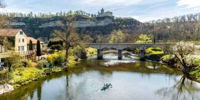Ilmtal-Radweg – vier Tage durchs schöne Thüringen Flusslandschaft mit Ruderboot, Brücke und Anwesen unter einer Burgruine.