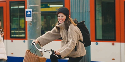 Revolutionäre Sicherheit im urbanen Radverkehr mit Inflabi. Frau auf Fahrrad fährt neben Zug.