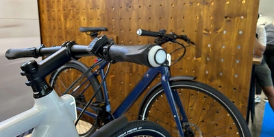 Die Fahrräder und E-Bikes von Ellipse kommen bereits mit integrierter Beleuchtung für Tag und Nacht Zwei Fahrräder vor einer Holzwand mit integrierter Lenkerbeleuchtung