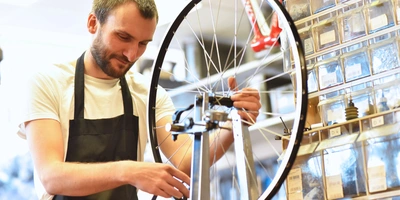 Mechaniker zentriert Laufrad eines Fahrrades in der Werkstatt 