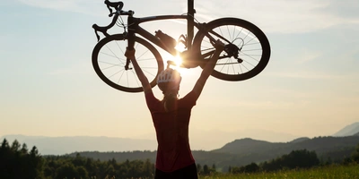 Frau hält ihr Rennrad triumphal in die Luft