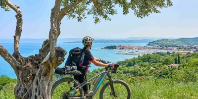 Mann steht neben Fahrrad und blickt über Stadt.