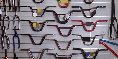 Lenkerarten Fahrrad: Diese Fahrradlenker Typen gibt es Eine Wand mit verschiedenen Fahrradlenkern in unterschiedlichen Farben und Designs.