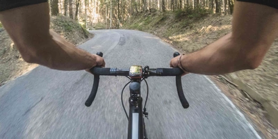Mann auf Rennrad fährt auf Straße durch Wald.