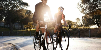 Mann und Frau mit Helm fahren auf Rennrad.